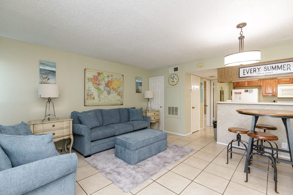 Relax in your bright, beachy living space featuring comfy blue sofas and a fully equipped kitchen for memorable vacation meals together.