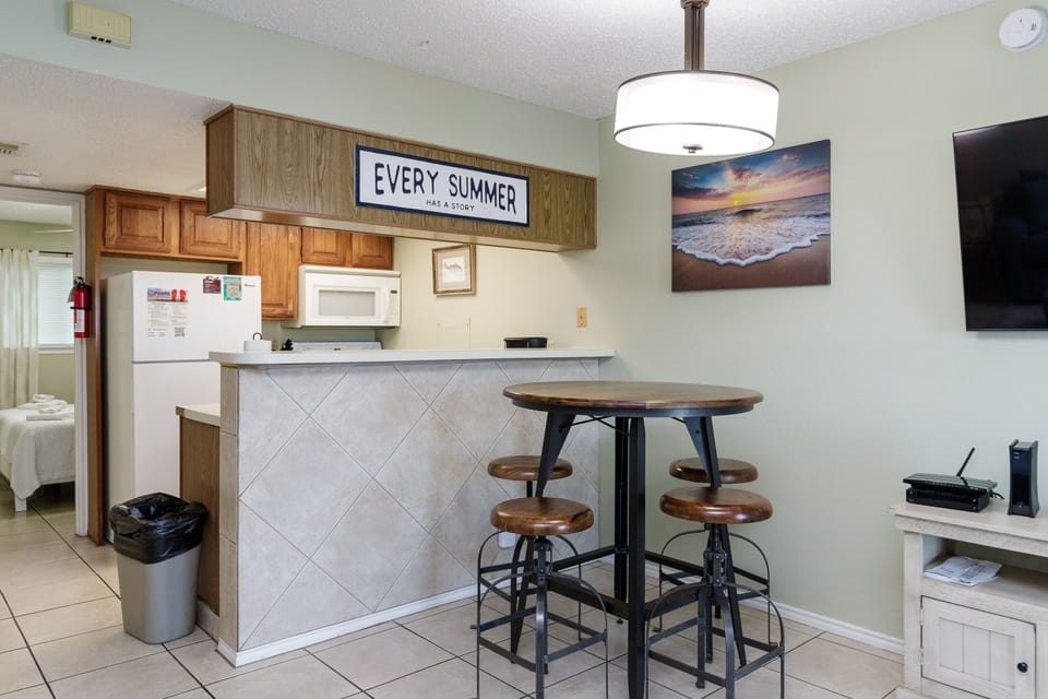 Your bright kitchen features coastal charm with beach artwork and a cozy breakfast bar for morning coffee.
