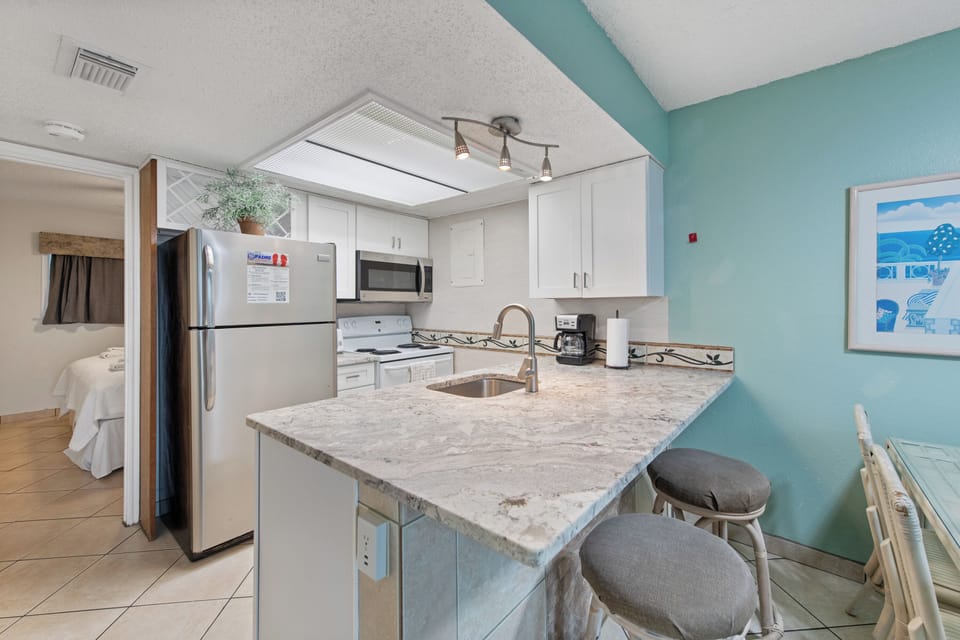 Your fully equipped kitchen features modern appliances, granite countertops, and a breakfast bar where you can enjoy coffee while planning your beach adventures.