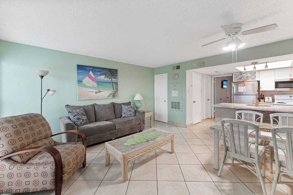 Relax in your coastal-themed living space with comfy seating and open kitchen, perfect for unwinding after beach adventures.
