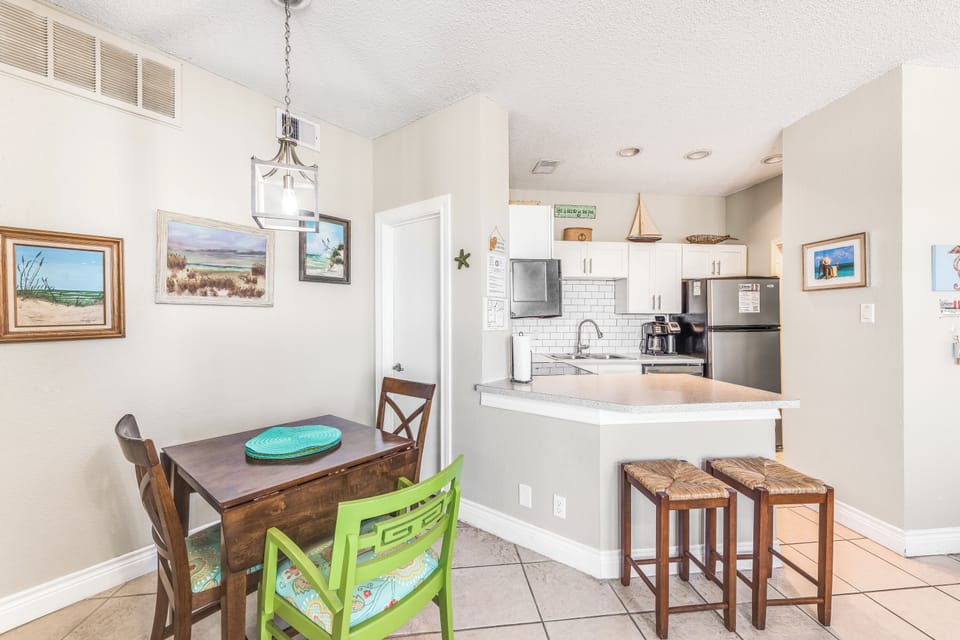 Your open-concept kitchen and dining space features modern appliances, coastal artwork, and cheerful seating perfect for morning coffee or casual meals.