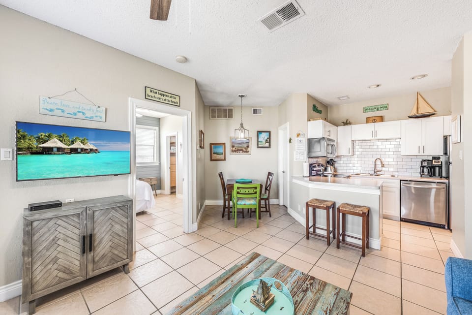 Your bright coastal-inspired space features an open kitchen with modern appliances, cozy dining nook, and beach-themed decor that instantly puts you in vacation mode.