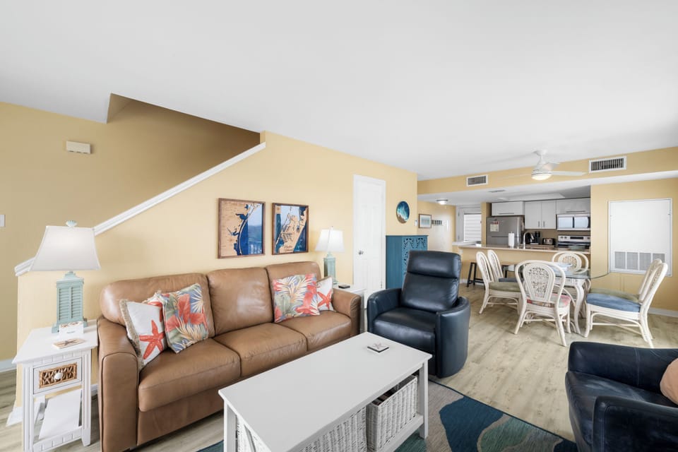 Relax in your bright, tropical-themed living space with comfortable seating and an open kitchen perfect for your beach getaway.