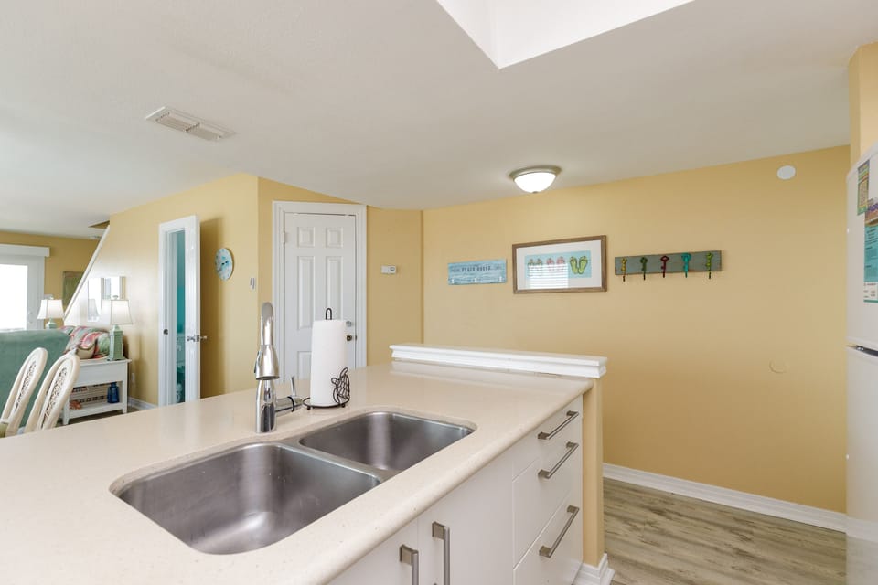 Your bright kitchen features a double-basin sink and coastal charm, perfect for preparing meals after beach adventures.