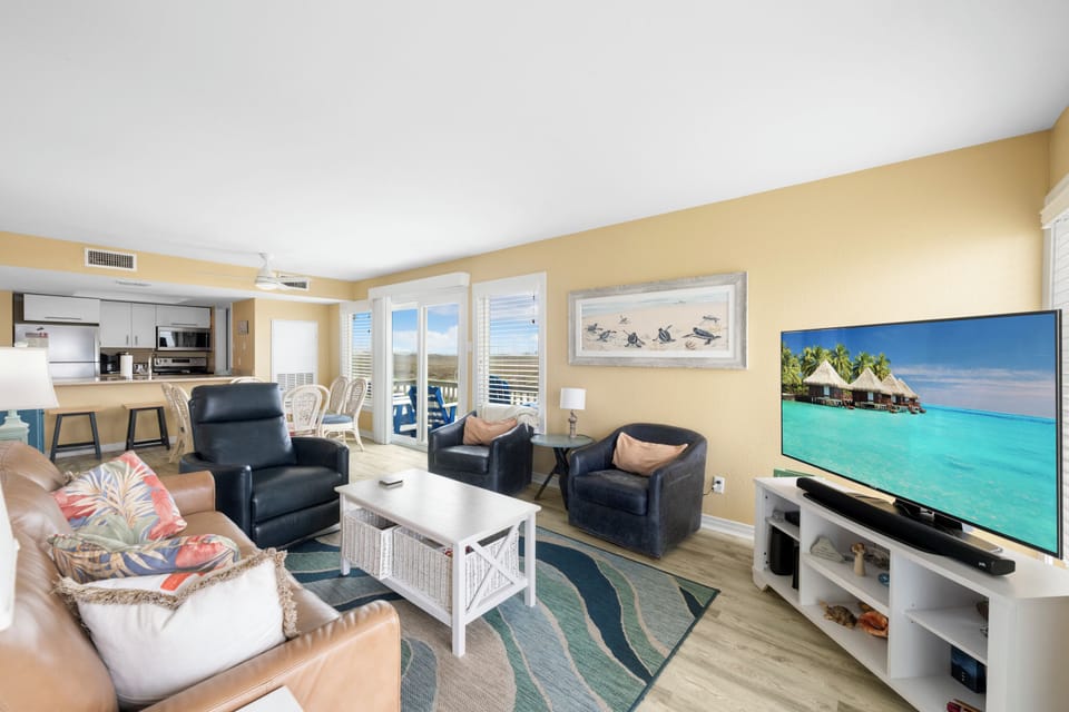 Your bright coastal living space blends comfort with ocean charm, featuring vibrant tropical accents and an open kitchen perfect for vacation gatherings.