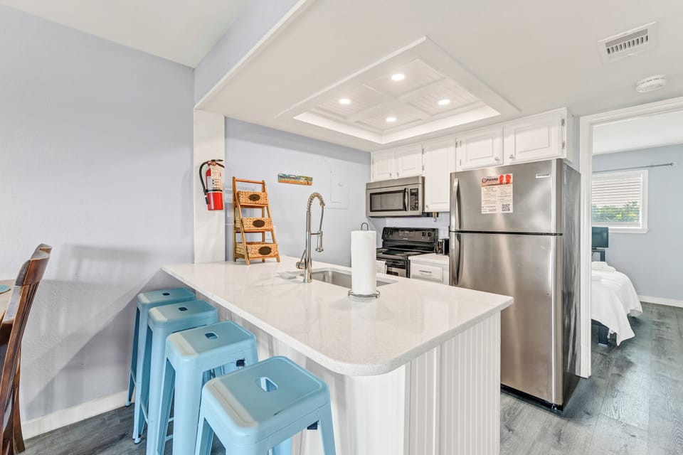 Your bright kitchen features modern stainless appliances, marble countertops, and cheerful blue stools perfect for morning coffee or casual meals.
