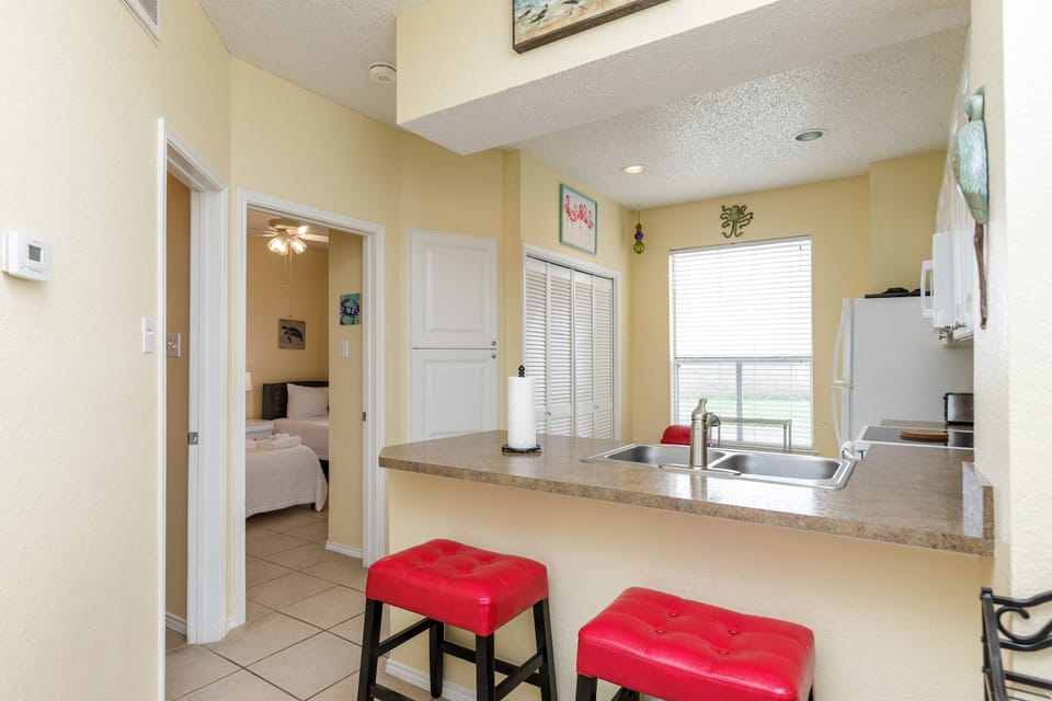 Step into your spacious kitchen with granite countertops and bright red bar stools, perfect for morning coffee or casual dining.