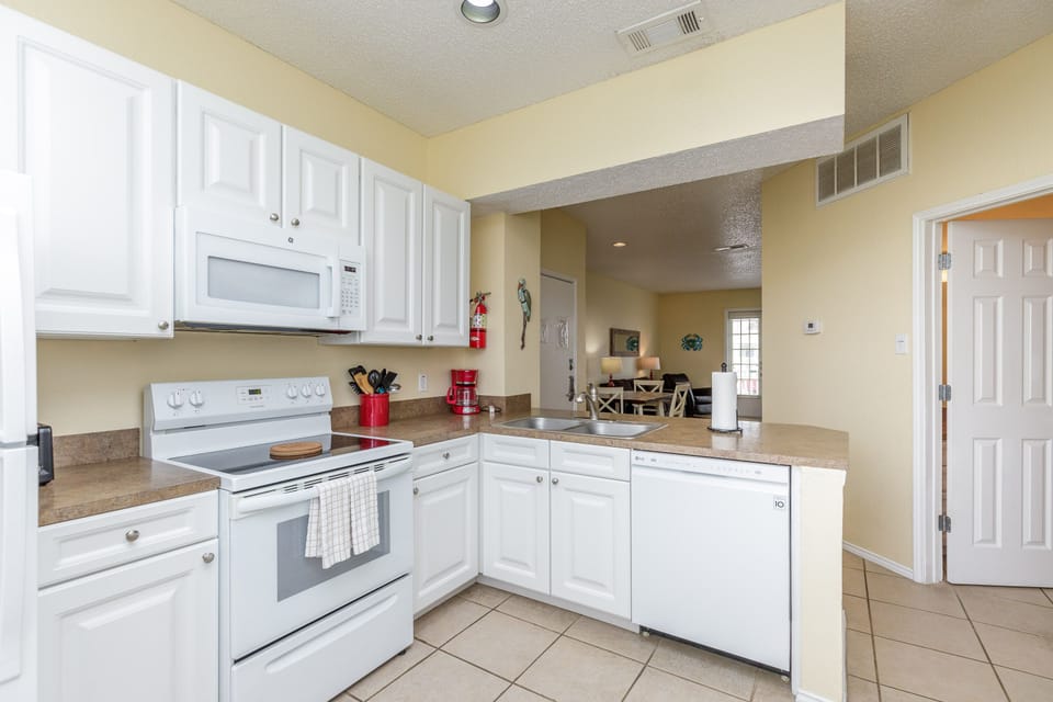 Your fully equipped kitchen awaits with white appliances, granite counters, and everything needed for home-cooked meals during your stay.