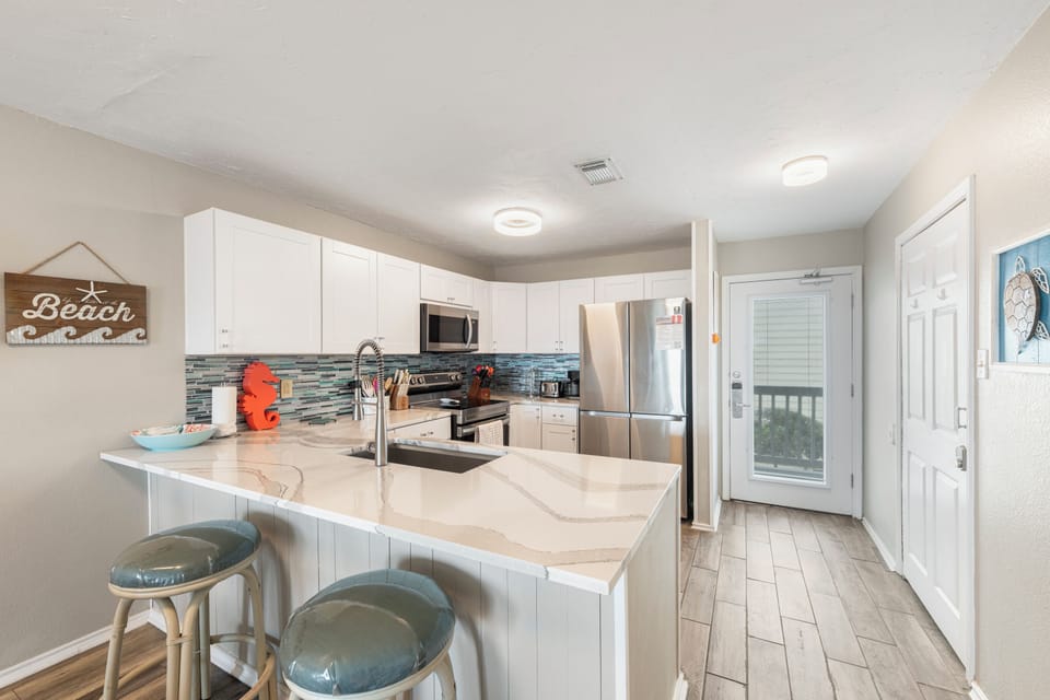 Your fully equipped kitchen awaits with modern appliances, granite countertops, and coastal charm perfect for preparing vacation meals together.