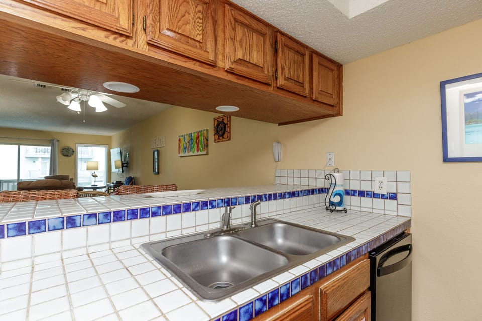 Your kitchen features warm wood cabinets and charming blue tile accents, perfect for preparing meals with a view of the living area.