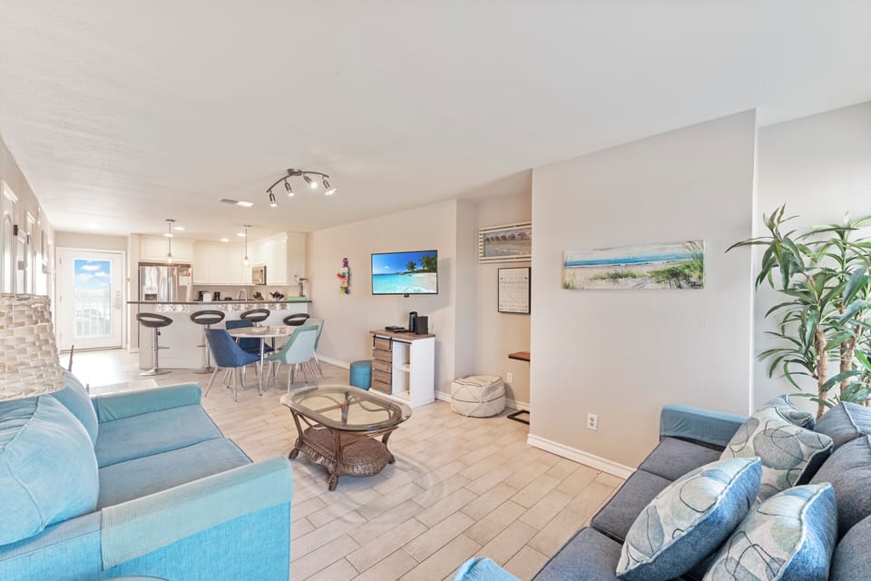 Relax in your bright open-concept space where coastal blue furnishings meet modern comfort, creating the perfect beach retreat atmosphere.