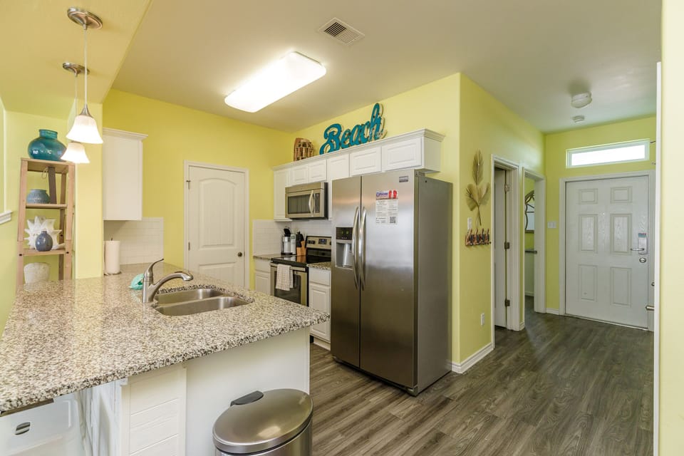 Your bright, fully-equipped kitchen awaits with granite countertops, stainless appliances, and cheerful yellow walls that make meal prep feel like vacation.