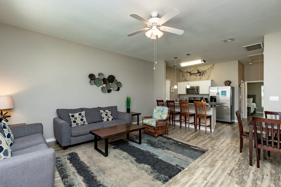 Relax in your spacious open-concept living area where modern comfort meets coastal charm, complete with cozy seating and a fully equipped kitchen.