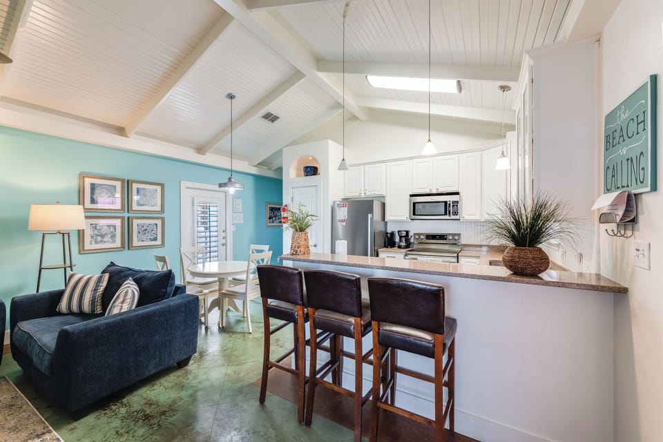 Relax in your coastal-inspired open living space with soaring beamed ceilings, fully equipped kitchen, and beach-themed décor perfect for vacation memories.