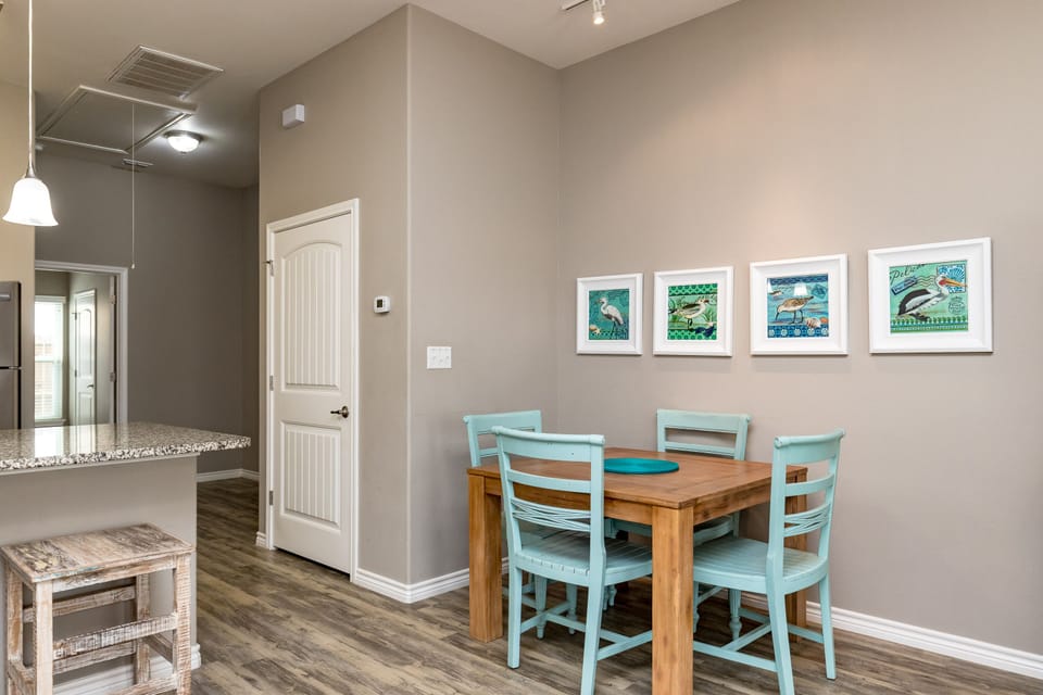 Your cozy dining nook features a warm wood table with cheerful turquoise chairs, perfect for morning coffee or intimate meals together.