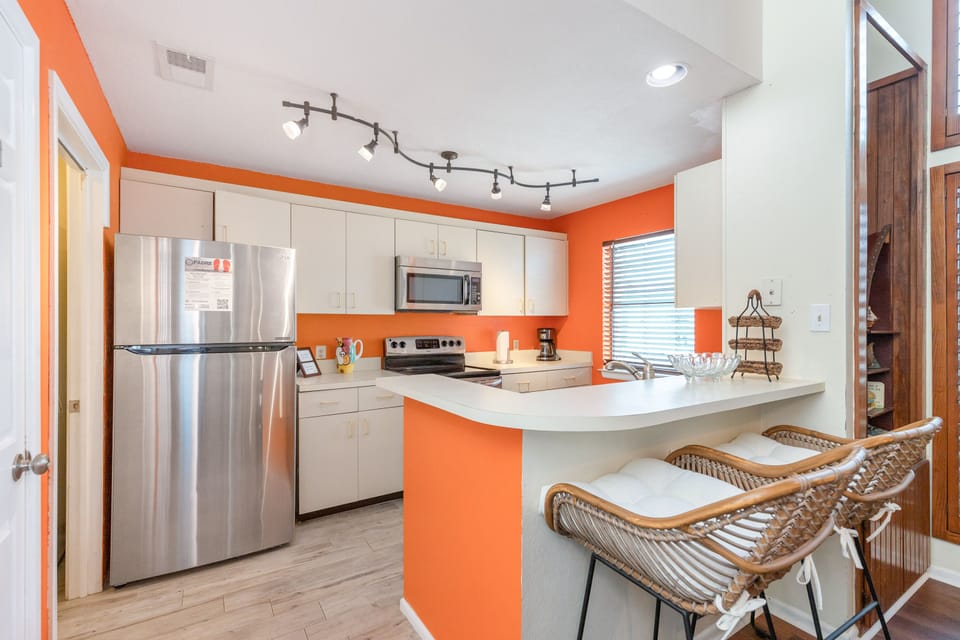 Your vibrant kitchen awaits with modern appliances and stylish orange accents, perfect for preparing meals together.