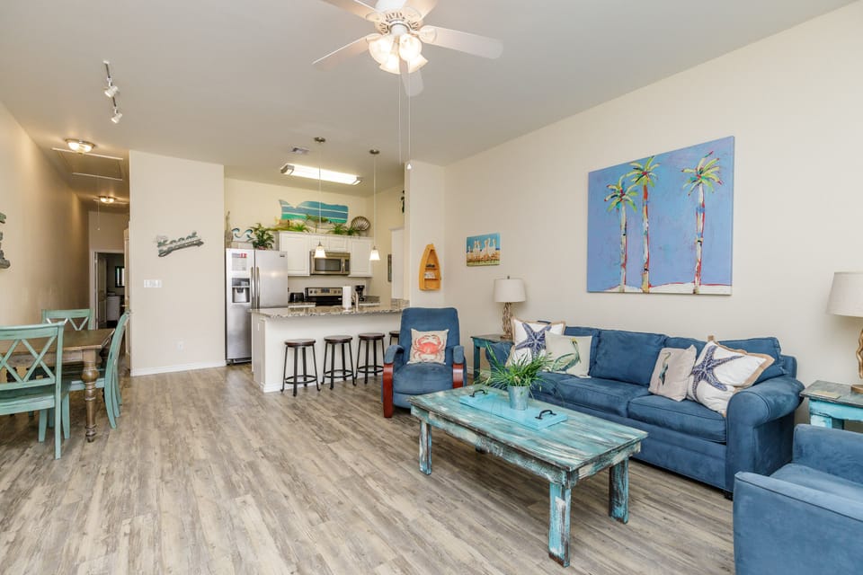 Relax in your coastal-themed living space with comfortable blue seating and beach artwork creating a serene atmosphere.