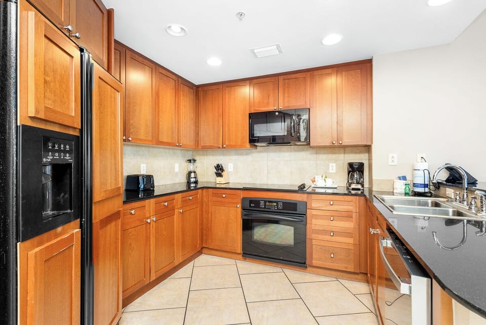 Prepare your favorite meals in this spacious, fully equipped kitchen featuring warm wood cabinetry, modern appliances, and ample counter space for all your culinary adventures during your stay.