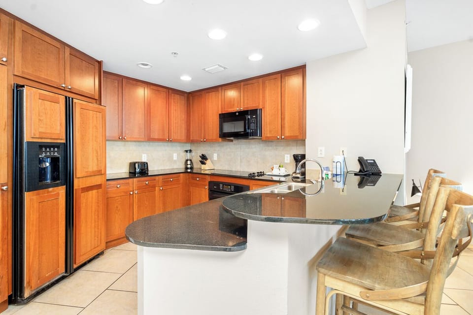 Your fully-equipped kitchen with warm wood cabinetry, granite countertops, and modern appliances awaits—perfect for preparing meals and gathering with loved ones during your stay.