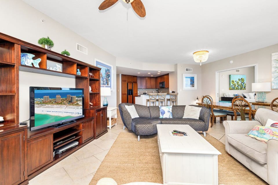Settle into your spacious living area, where coastal charm meets comfort with open views into the kitchen and dining space—perfect for gathering after a day at the beach.