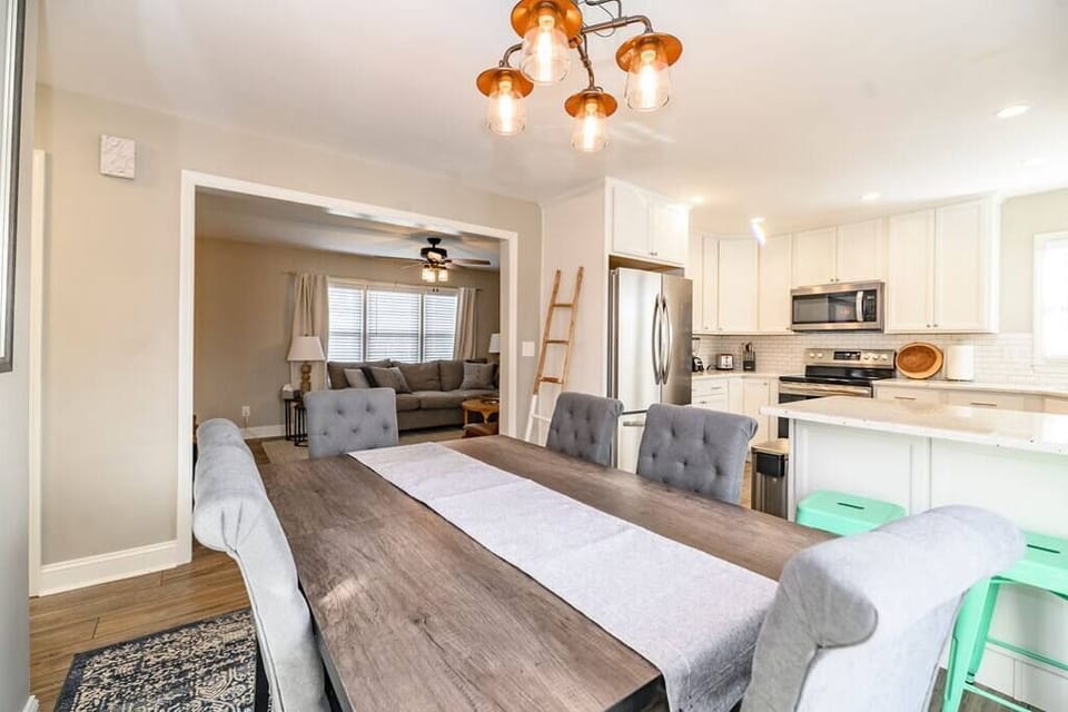 Stunning open-concept dining area connected to a modern kitchen with stainless steel appliances and cozy living room seating, perfect for family meals and entertaining.
