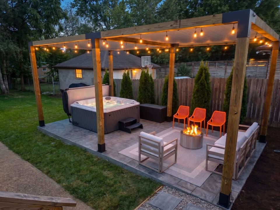 Pull
two chairs up
to the fire pit
while the hot
tub steams a
few feet away
— string lights
overhead, the
whole pergola
built for
exactly this
kind of night.