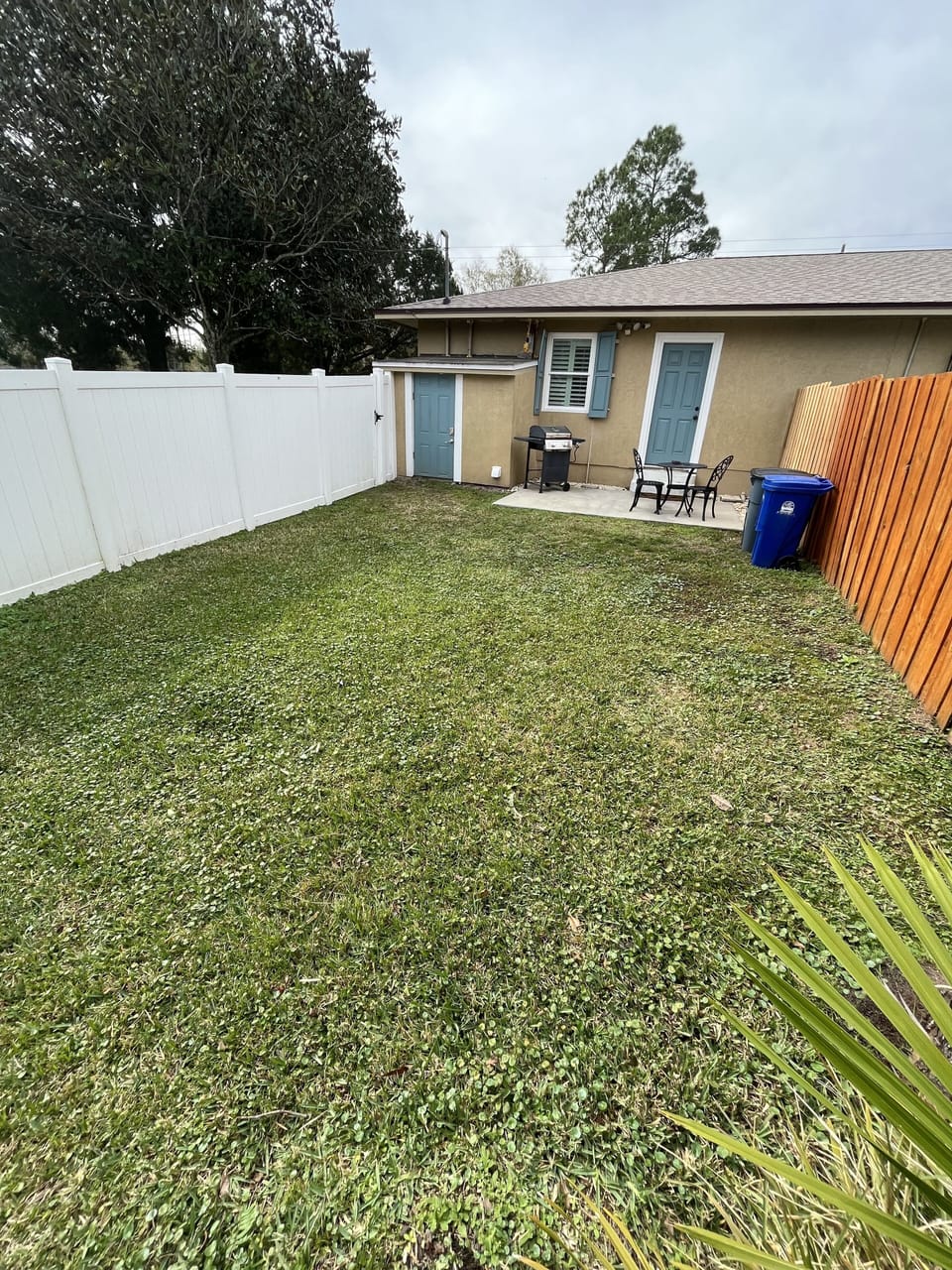 Private fenced backyard with patio seating and convenient laundry shed