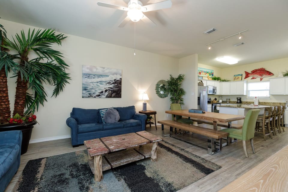 Relax in your bright open living space featuring coastal décor, comfy seating, and a fully-equipped kitchen perfect for memorable meals.