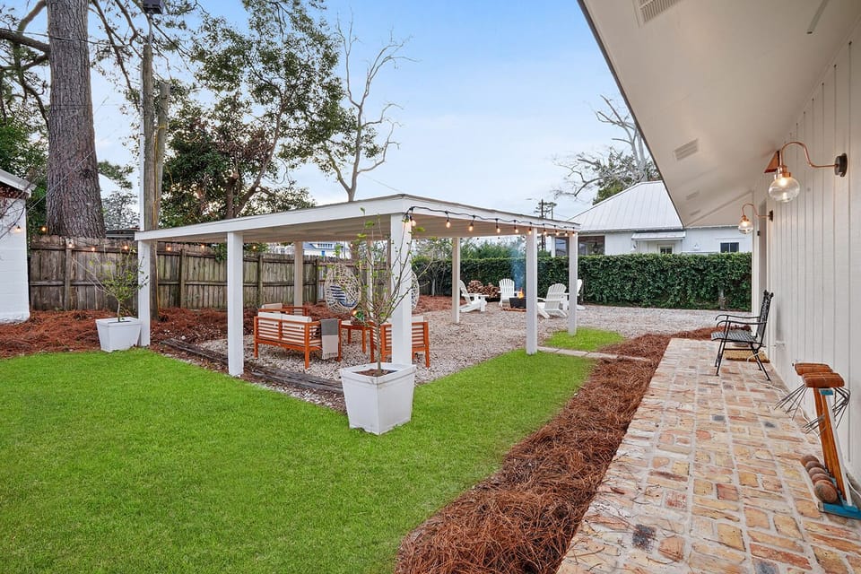 Covered patio with teak furniture, swings, Adirondack chairs, grill & fire pit. 