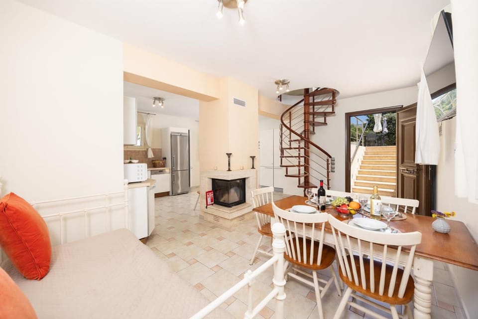 Open-plan living room with sofa, dining area, kitchen, ornamental fireplace, A/C, WiFi internet, and satellite TV