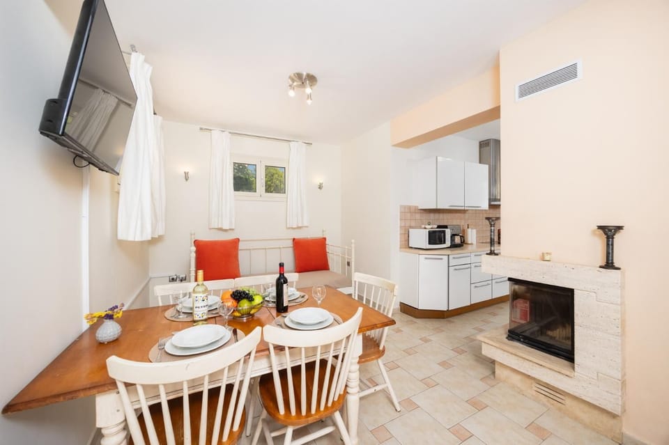 Open-plan living room with sofa, dining area, kitchen, ornamental fireplace, A/C, WiFi internet, and satellite TV
