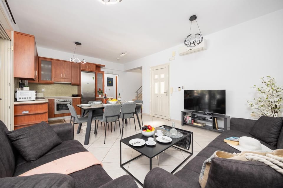 Open-plan living room with sofas, dining area, kitchen, A/C, WiFi internet, and satellite TV