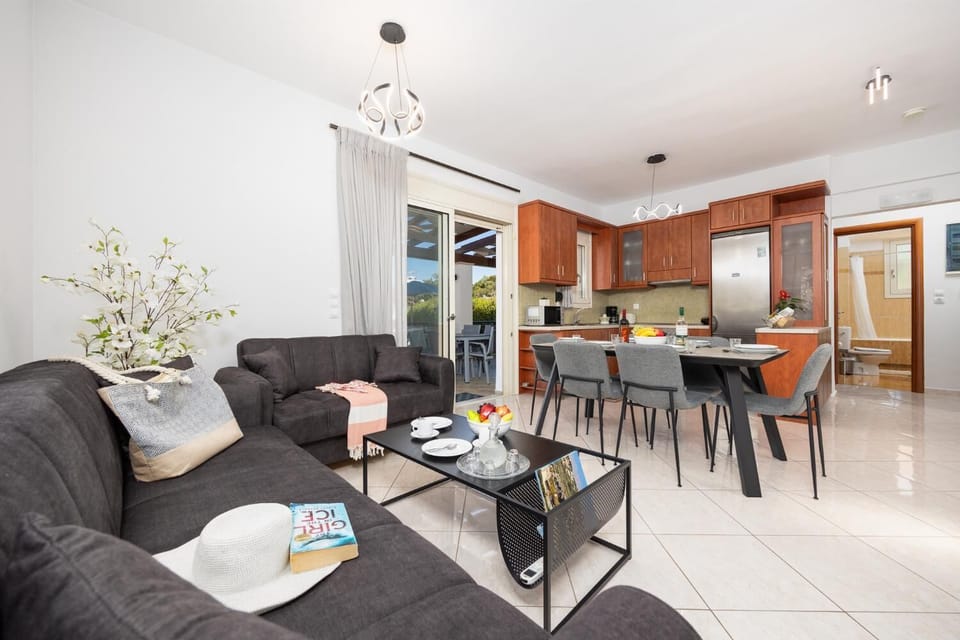 Open-plan living room with sofas, dining area, kitchen, A/C, WiFi internet, and satellite TV
