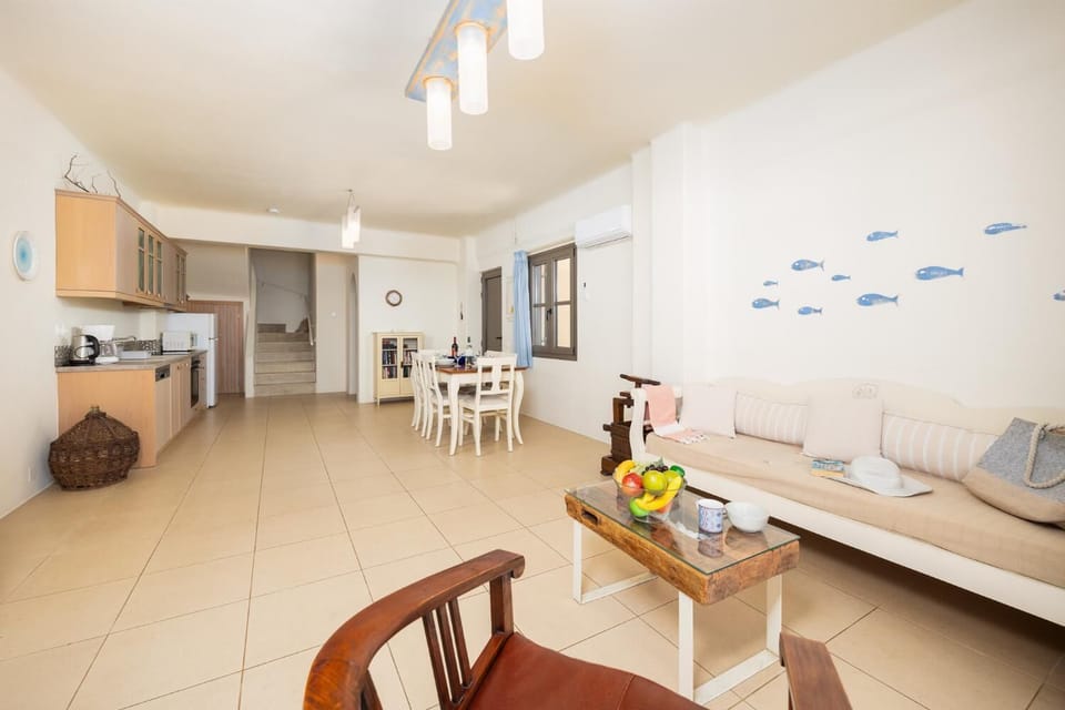 Open-plan living room with sofa, dining area, kitchen, ornamental fireplace, A/C, WiFi internet, and satellite TV