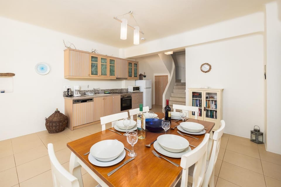 Open-plan living room with sofa, dining area, kitchen, ornamental fireplace, A/C, WiFi internet, and satellite TV