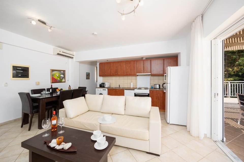 Open-plan living room with sofa, dining area, kitchen, A/C, WiFi internet, and satellite TV