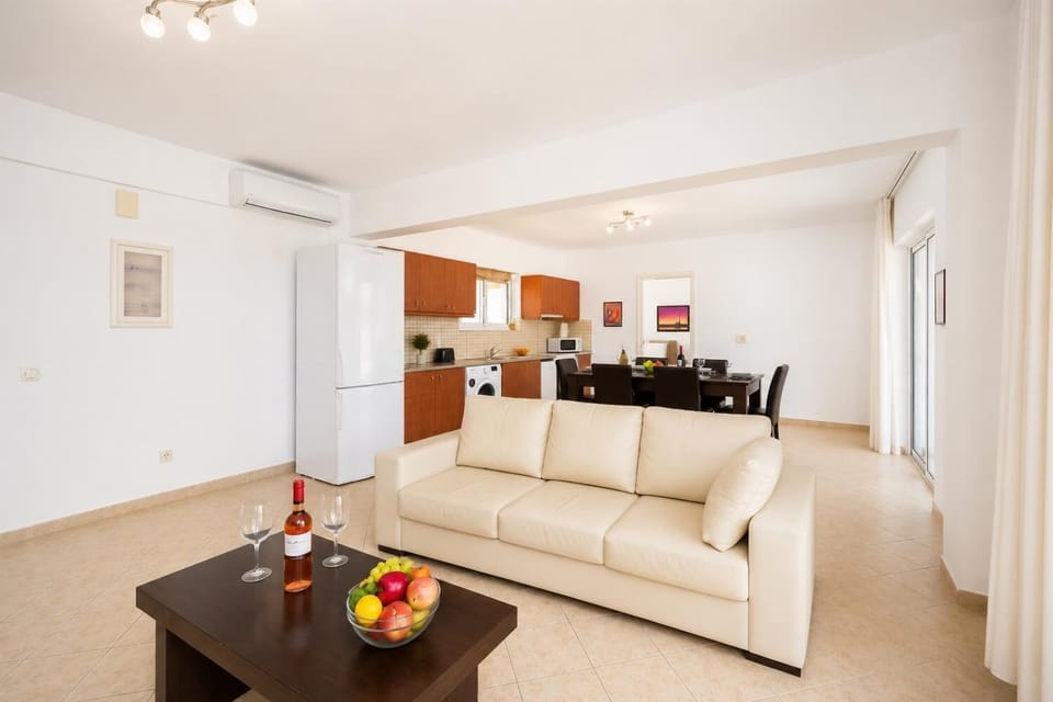 Open-plan living room with sofa, dining area, kitchen, A/C, WiFi internet, and satellite TV