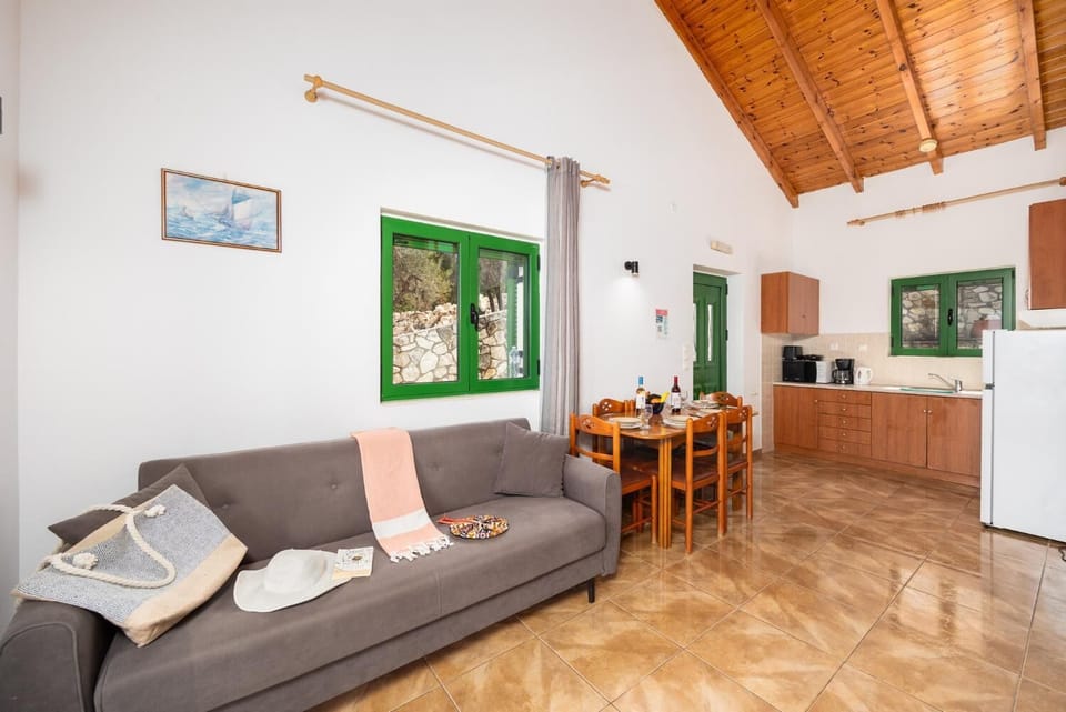 Open-plan living room with sofa, dining area, kitchen, A/C, WiFi internet, and satellite TV