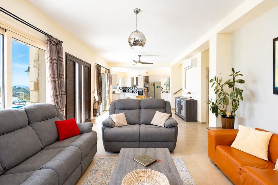 Bright open-plan living area with comfortable sofas, modern kitchen, and lovely pool terrace access.
