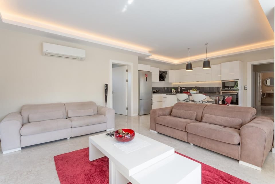 Open-plan living room with sofas, dining area, kitchen, A/C, WiFi internet, satellite TV, and DVD player