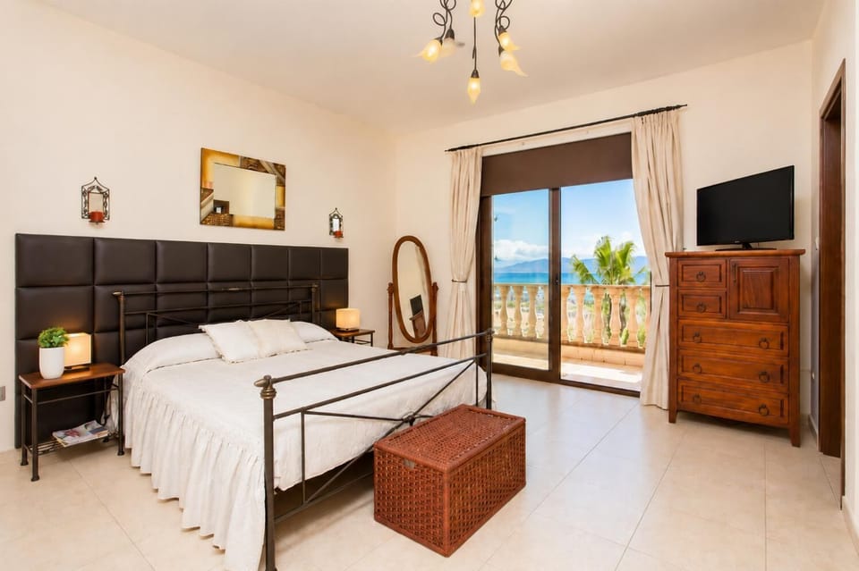 Double bedroom with en suite bathroom, A/C, TV, and balcony access with sea views