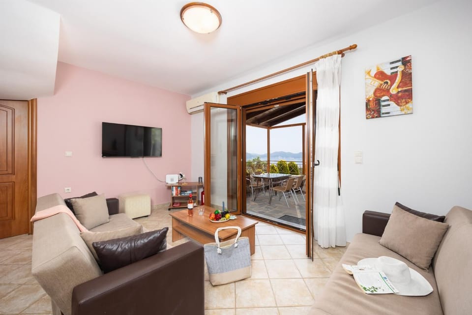 Open-plan living room with sofas, dining area, kitchen, ornamental fireplace, A/C, WiFi internet, and satellite TV