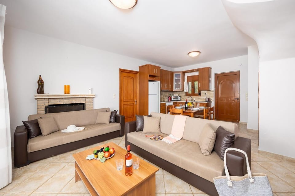 Open-plan living room with sofas, dining area, kitchen, ornamental fireplace, A/C, WiFi internet, and satellite TV