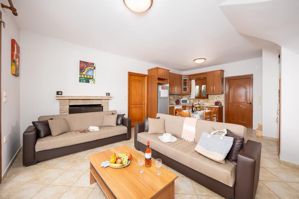 Open-plan living room with sofas, dining area, kitchen, ornamental fireplace, A/C, WiFi internet, and satellite TV