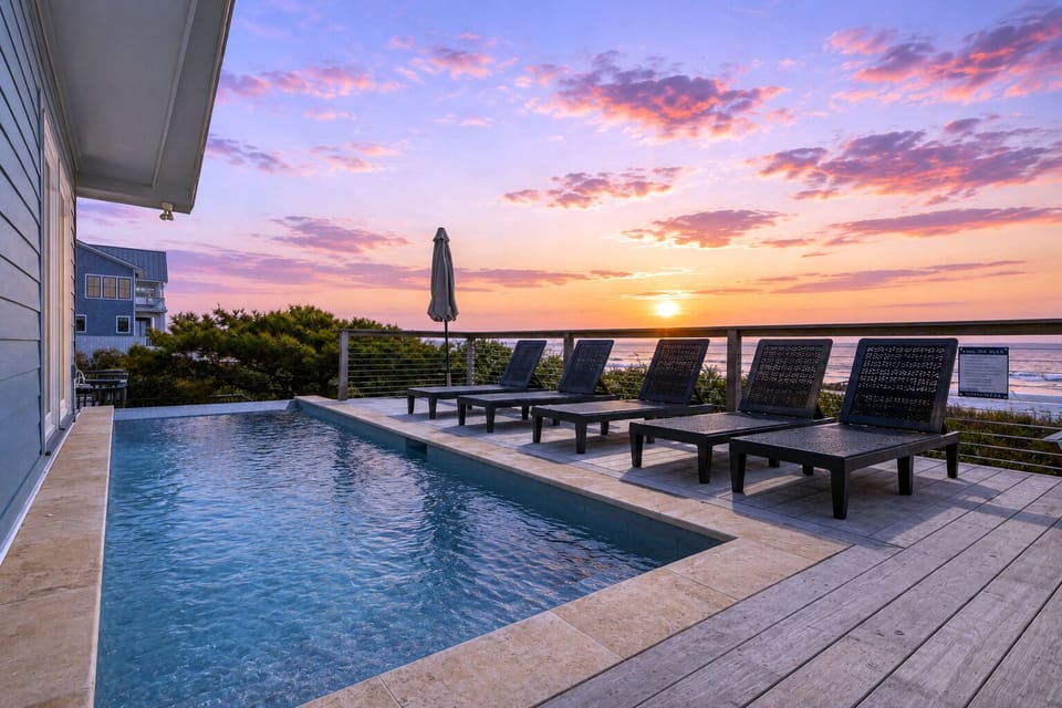 Expansive oceanfront deck featuring a private pool and lined with comfortable lounge chairs.