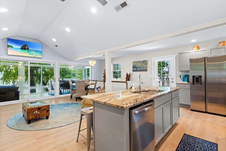 Bright open kitchen with large island, vaulted ceilings, and patio views