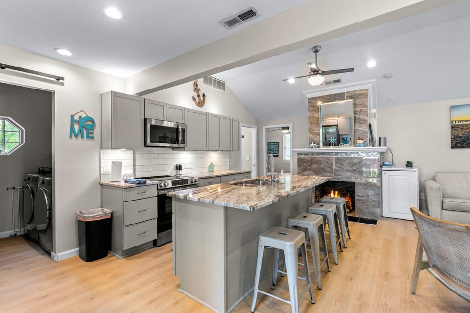 Bright open kitchen with granite island, bar seating & cozy fireplace