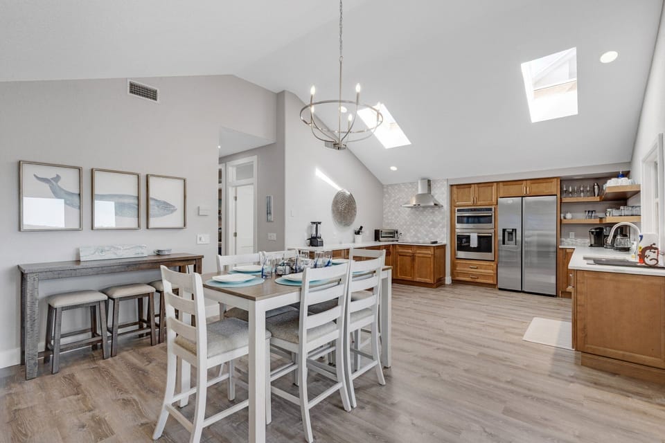 Kitchen and dining area with chandelier, dining table, kitchen island with bar stools, and stainless steel appliances