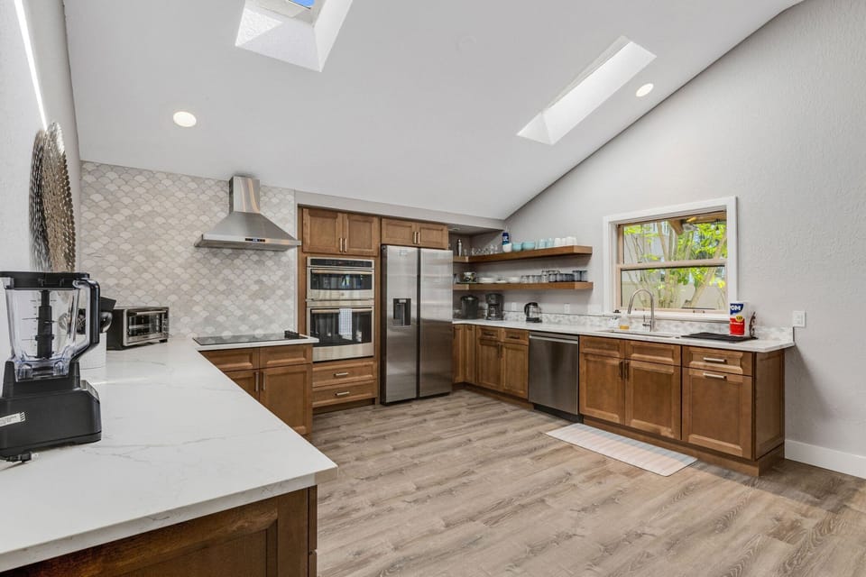 Kitchen with wood cabinets, stainless steel refrigerator, double ovens, and island with countertop seating