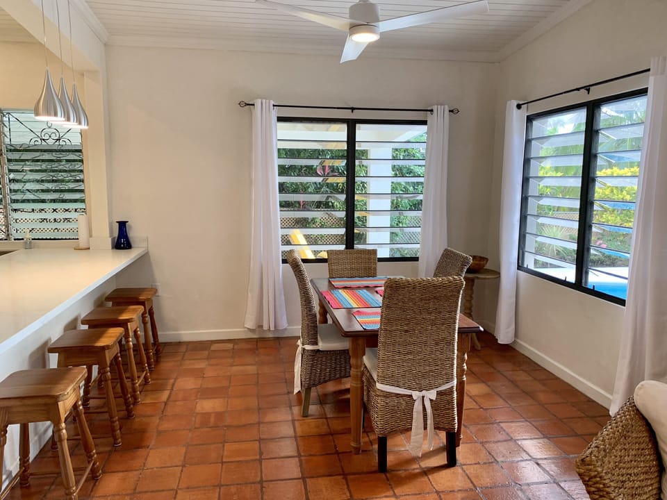 Dining room with large louvred windows facing pool deck and side covered patio